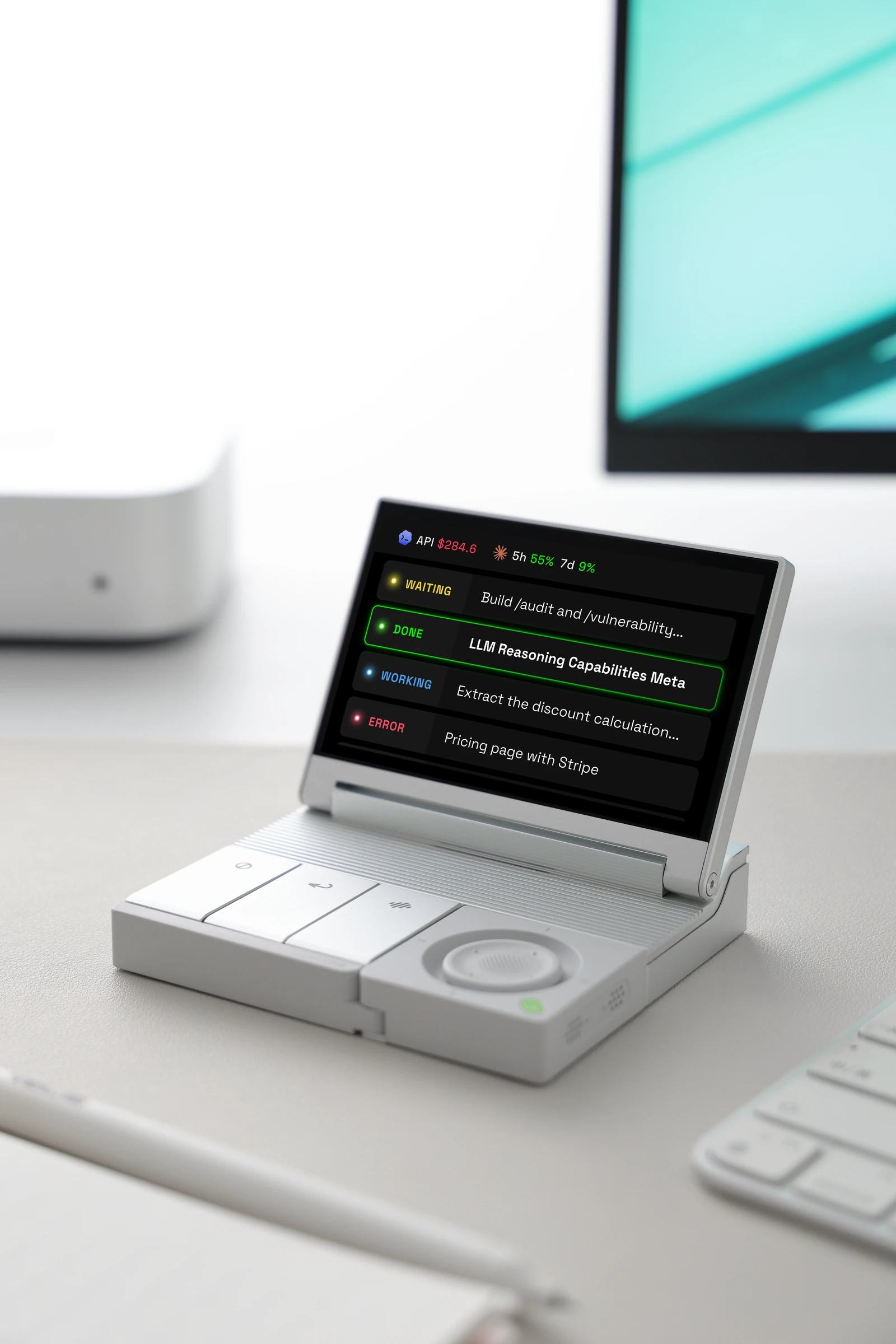 SlashVibe on a desk beside a monitor, displaying agent session statuses above its physical controls