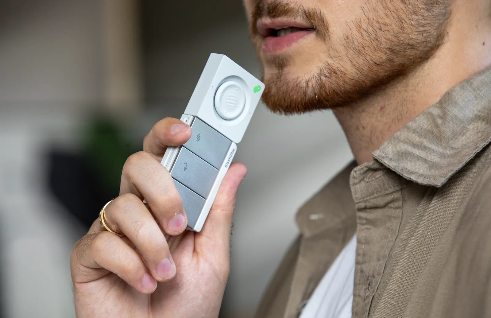 Someone holds the SlashVibe handheld close to their mouth and speaks into it